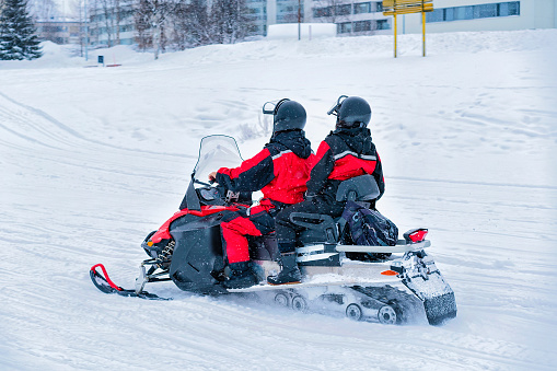 People in Snowmobile and Winter Finland, Lapland on Christmas. Extreme Sport Activity and Recreation in Cold Season.